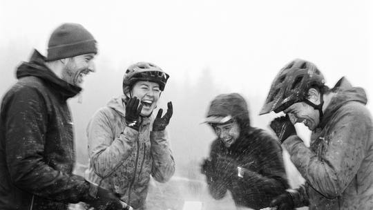 four riders at the bike wash, hosing each other as much as the bikes