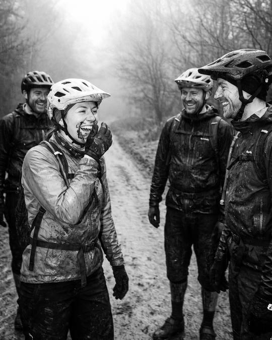 a rider in fits of laughter with three mates on a muddy forest track