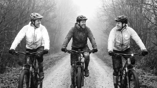 three mates riding side by side along a misty forest track, a sunday loop